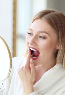 Woman looking at her gums in handheld mirror in Westfield