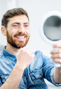 Patient smiling while looking in dental mirror